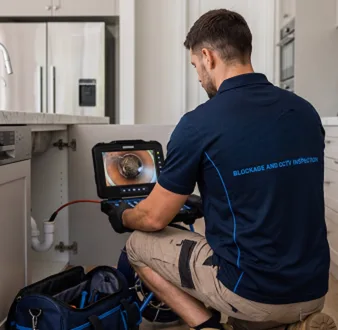Plumber clearing a blocked toilet in a Newport bathroom